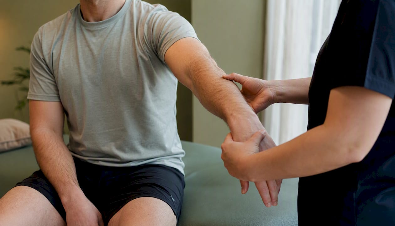 Therapist hands guiding patient arm exercise