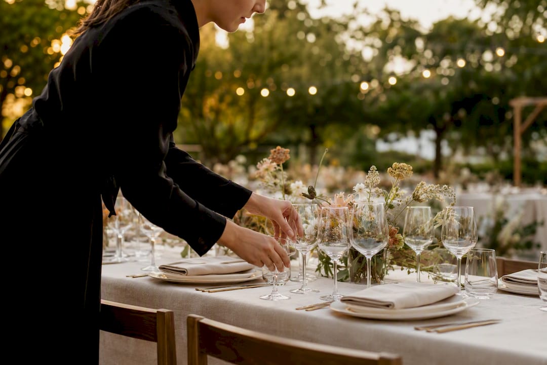Staff setting wine glasses on luxury table
