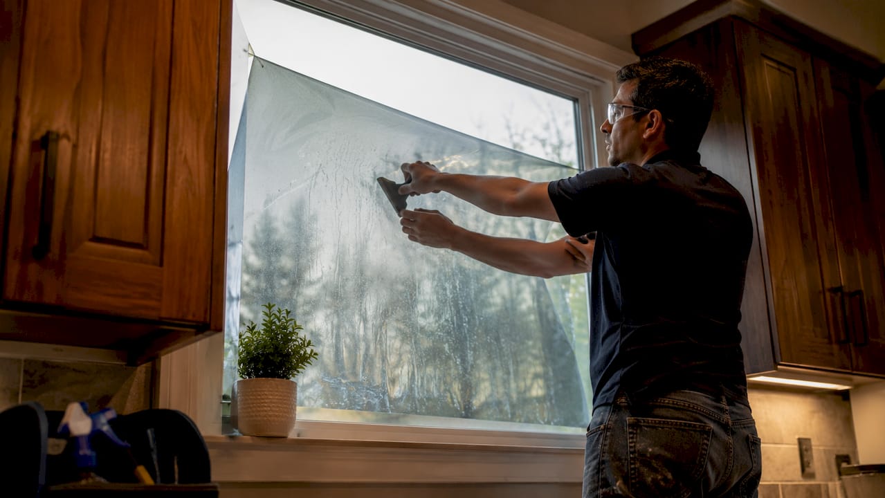 Installer applying privacy window film on home window