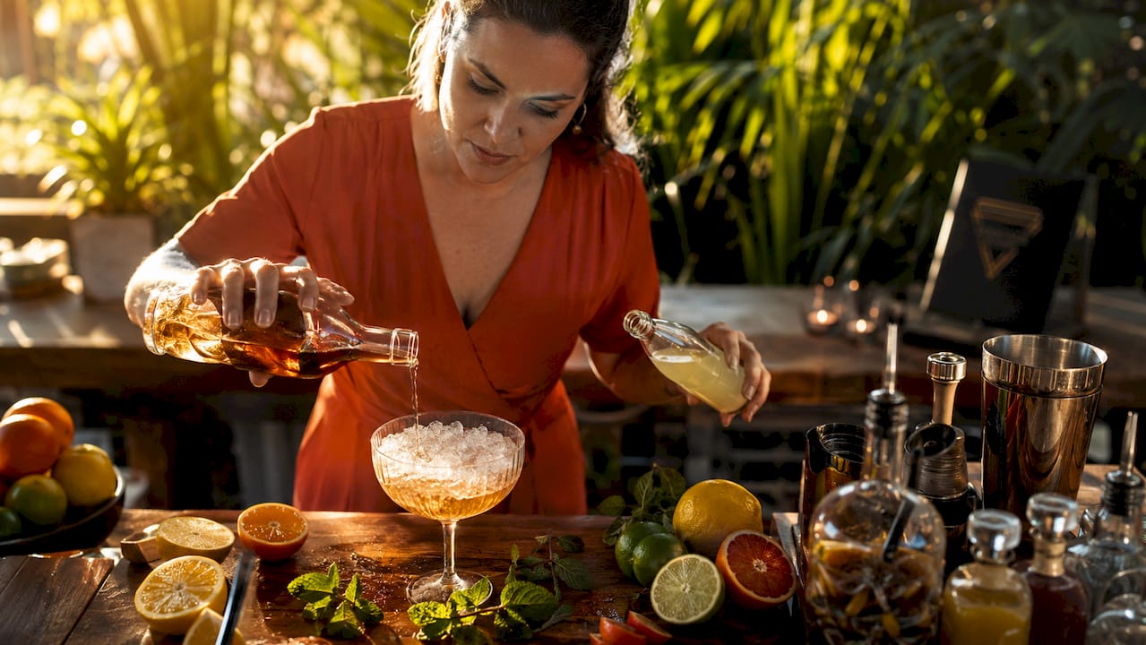 Van bovenaf gefotografeerde handen die een drankje klaarmaken op het aanrecht.