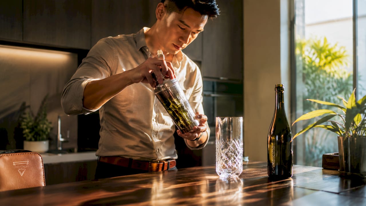 Man shaking a cocktail shaker to make a French 75