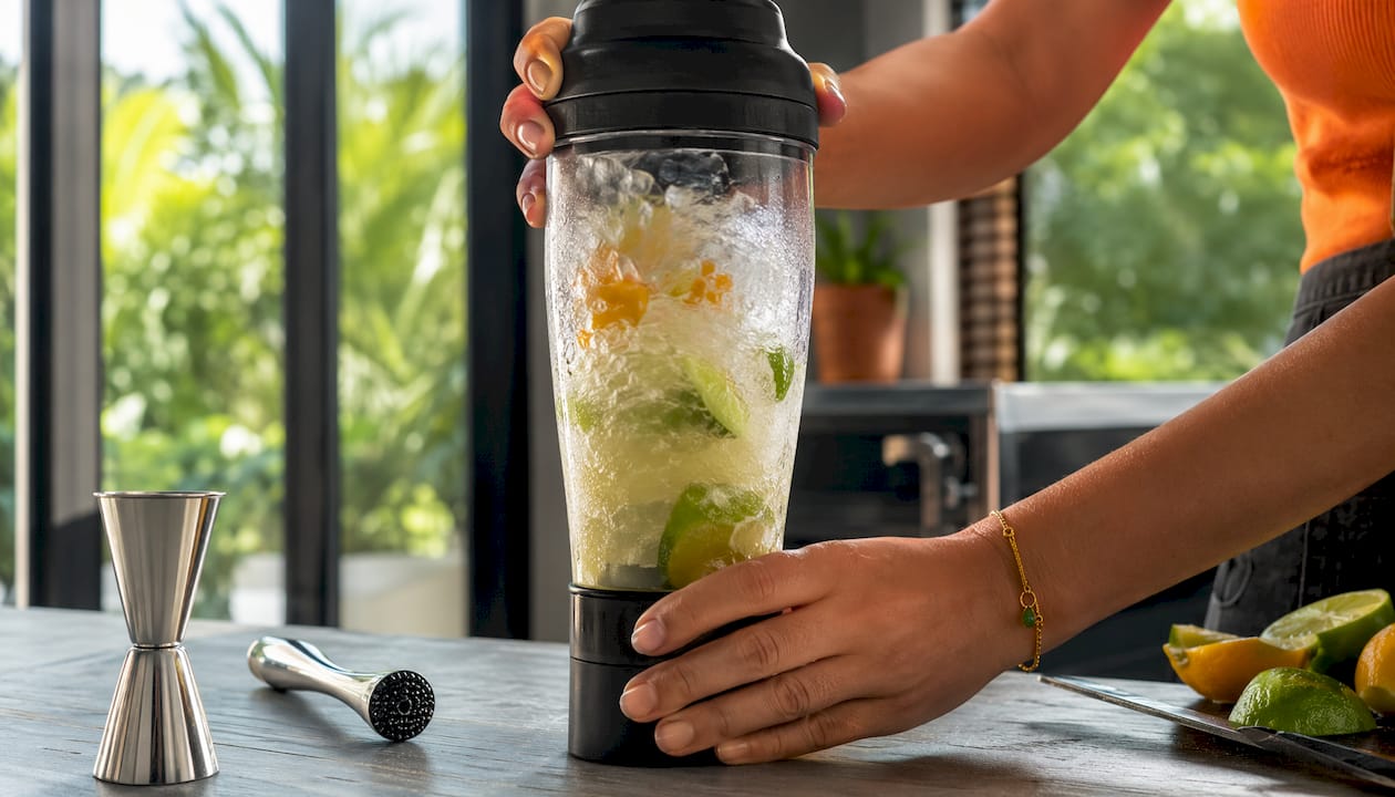 Hands blending ingredients for an ice-cold cocktail.