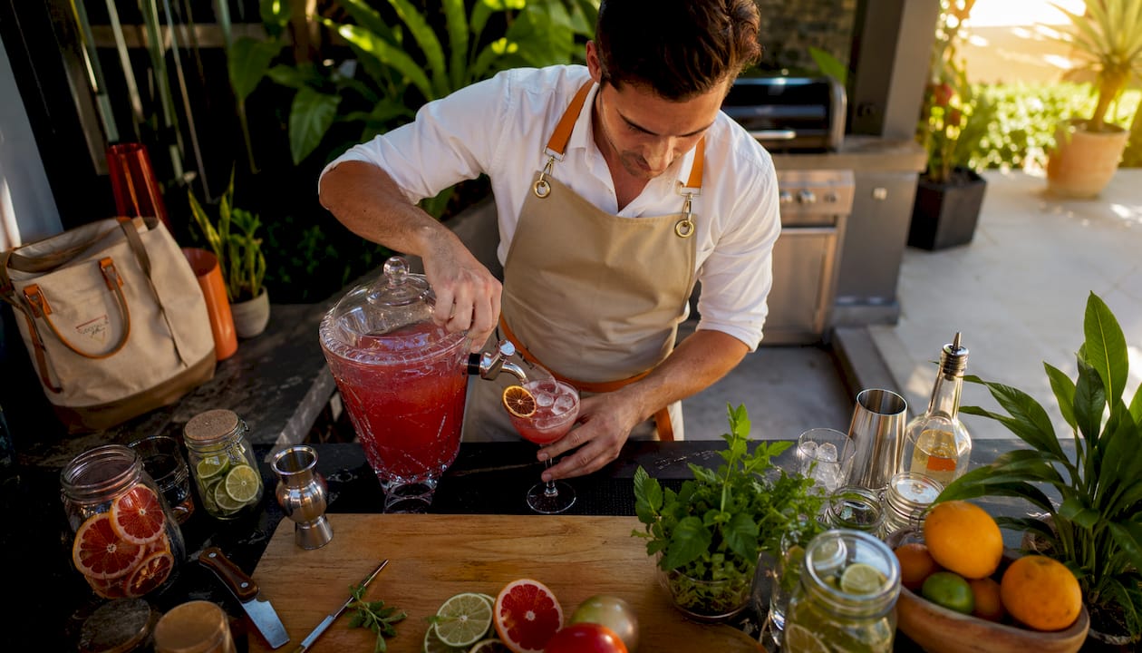 The bartender pours a homemade cocktail into a coupe glass.