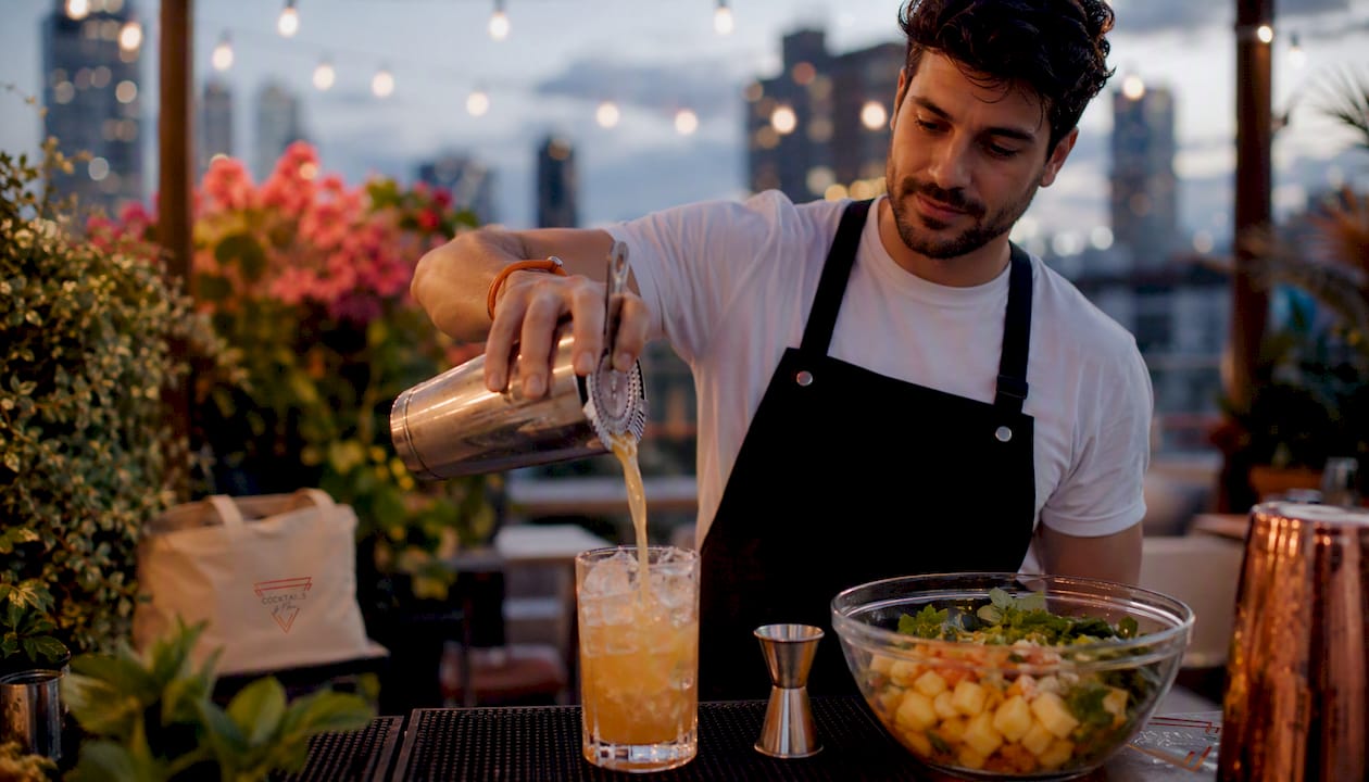 Een bartender staat buiten op een evenement een frisse mocktail te shaken.
