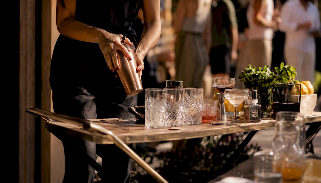 Een bartender staat op een evenement vakkundig cocktails te shaken voor de gasten.