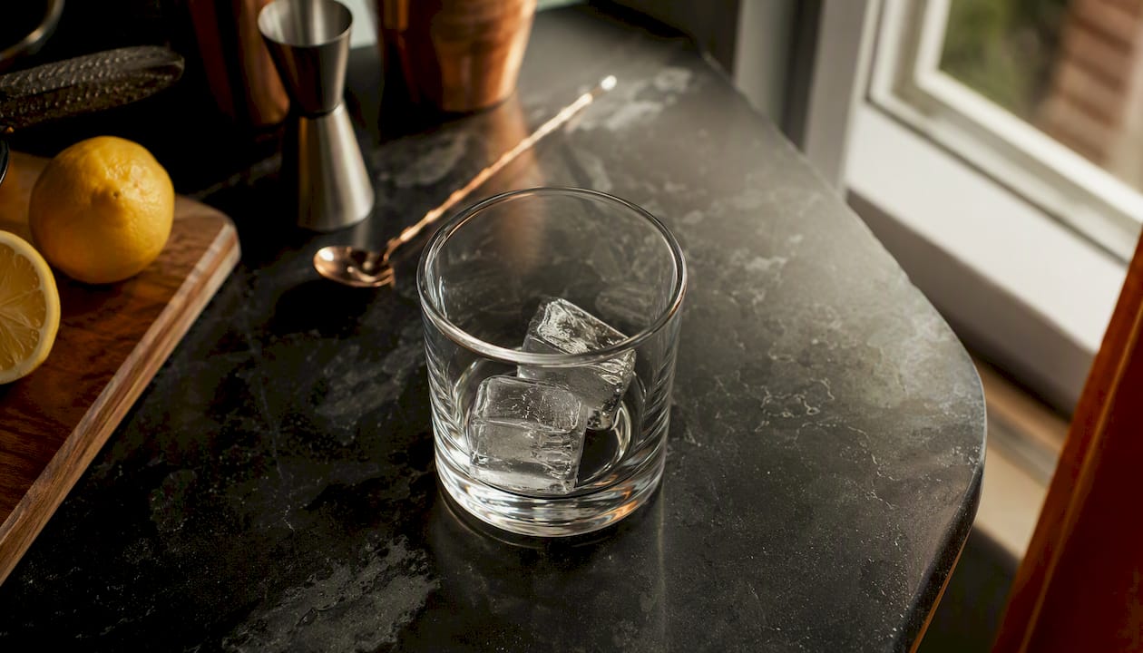 Een close-up van een tumblerglas gevuld met grote ijsblokken.