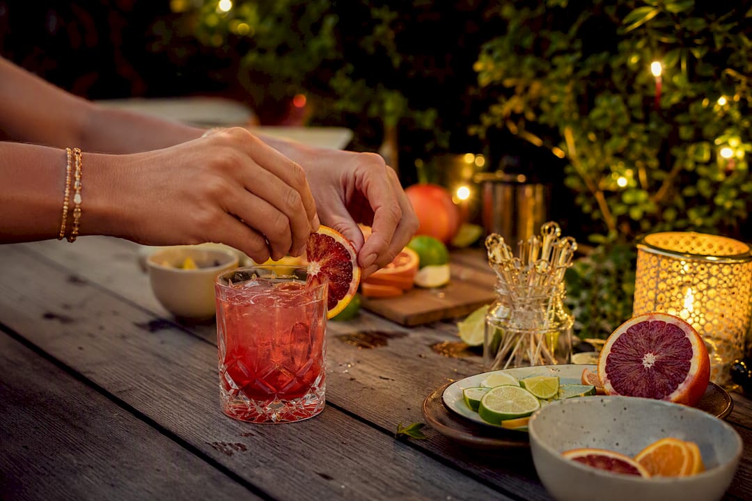 Een paar handen werkt een perfect geserveerde cocktail tot in de puntjes af met een mooie garnering.