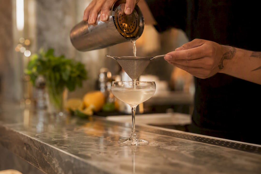 Cocktail wordt fijn gezeefd in een glas gegoten