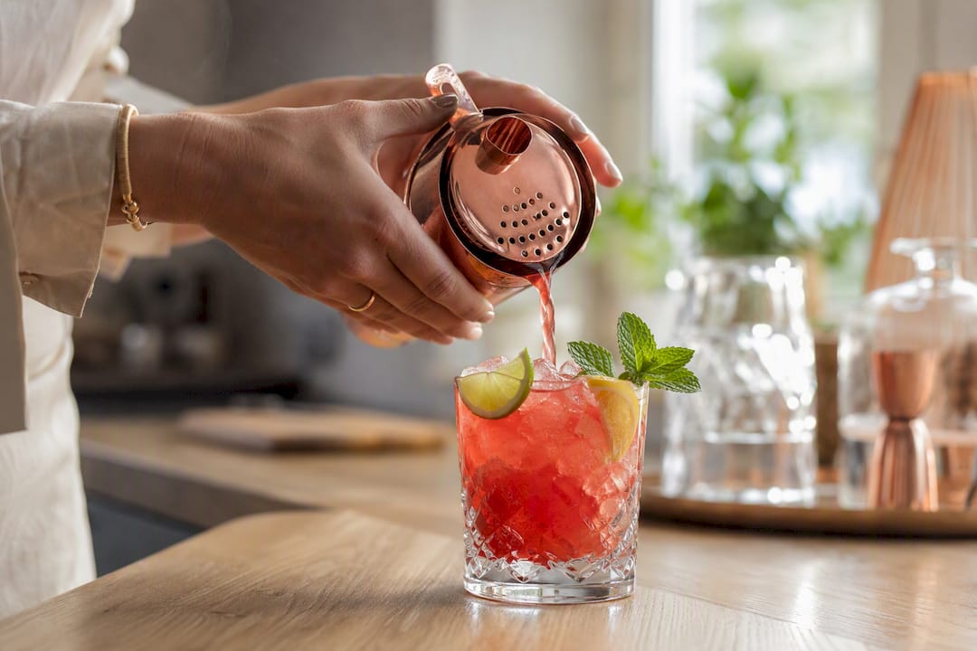 Handen die een feestelijke alcoholvrije mocktail inschenken