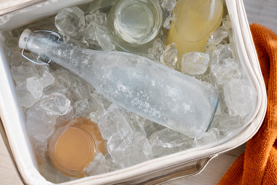 Bevroren waterfles tussen gekoelde drankflessen