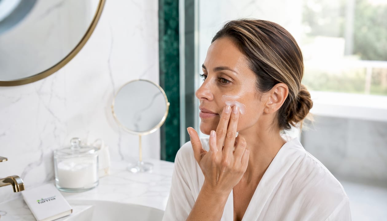 Aplicación de crema despigmentante en el rostro con las manos