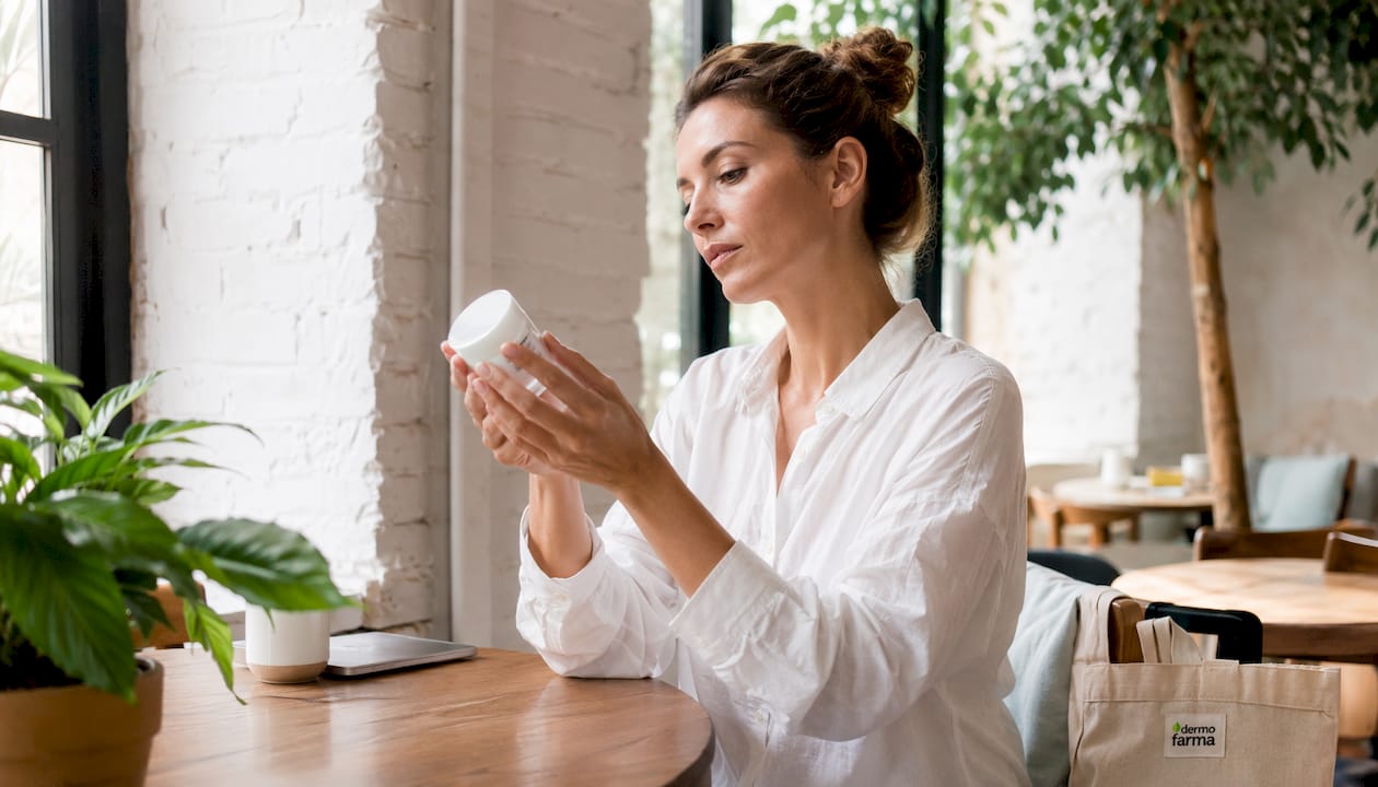 Una mujer observa detenidamente varios productos de dermocosmética que no tienen etiquetas.