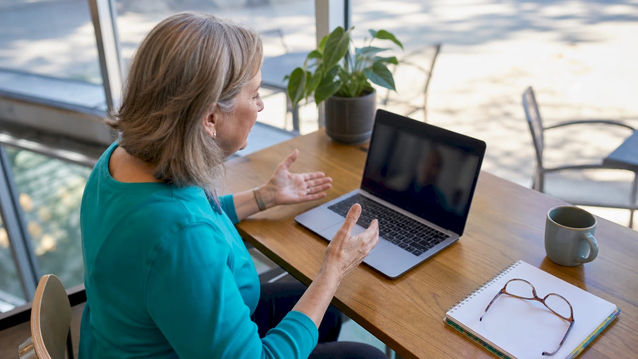 Solo older adult woman using telehealth on laptop
