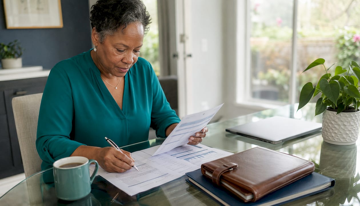 Solo ager reviewing financial documents at kitchen table