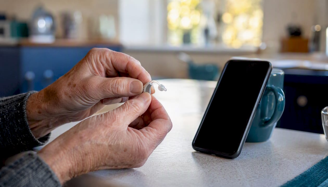 Hands pairing hearing aid to phone