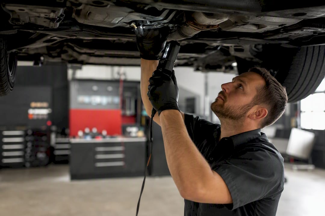 Technician hands inspecting vehicle undercarriage