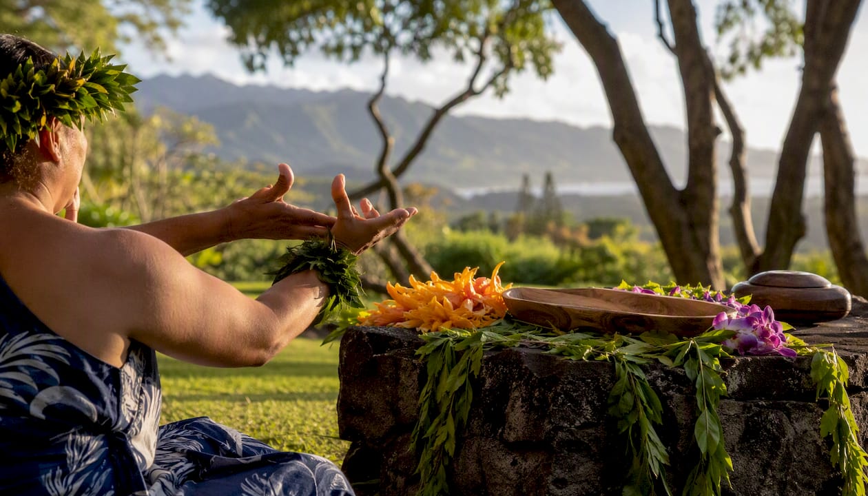 Hands performing Hawaiian cultural ritual outdoors