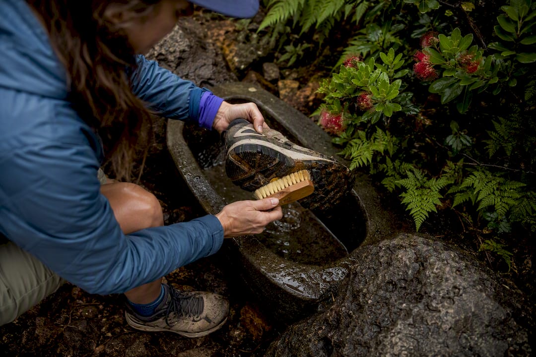 Traveler cleaning hiking shoes at forest trailhead