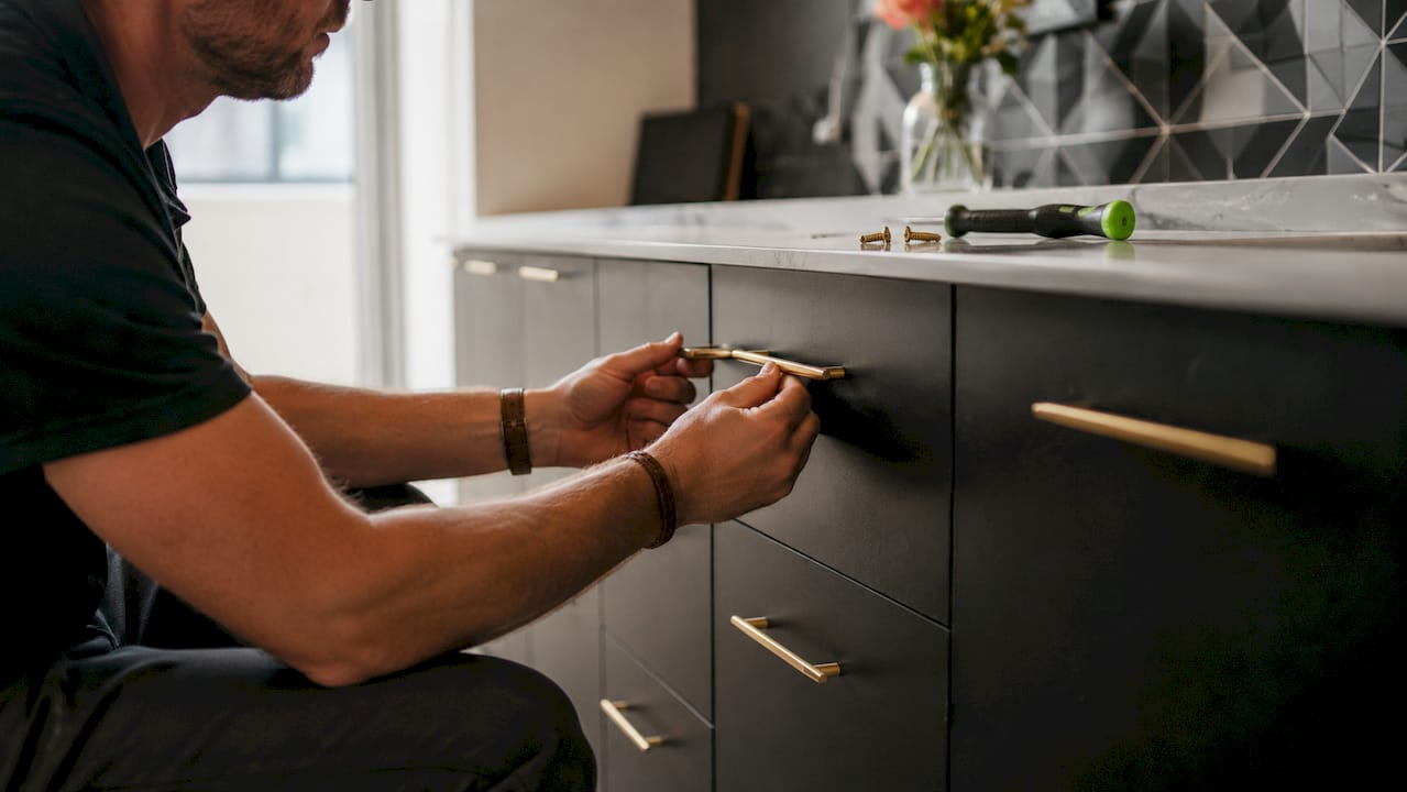 Hands installing new cabinet hardware