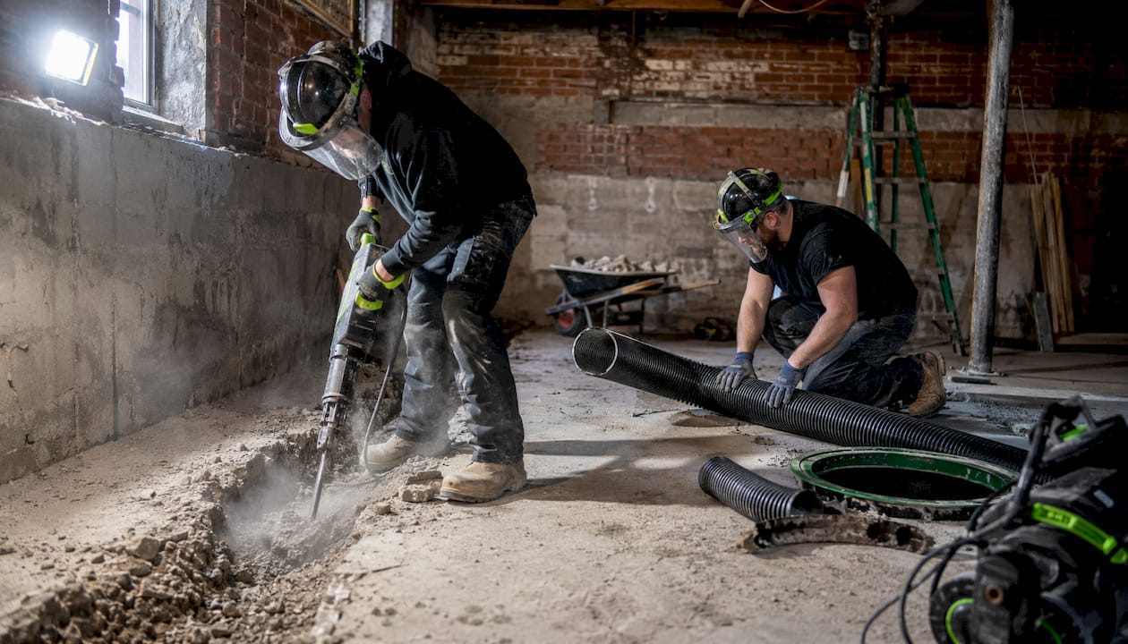 Workers installing basement interior drainage system