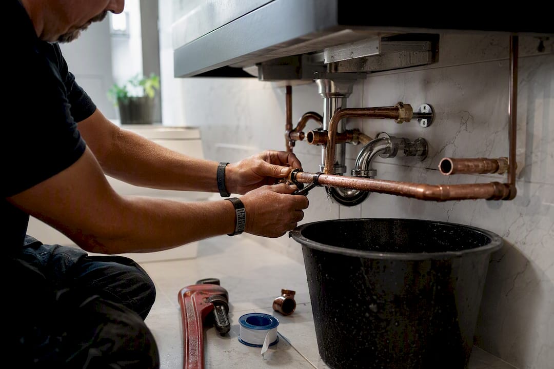 Hands relocating plumbing pipes in kitchen renovation