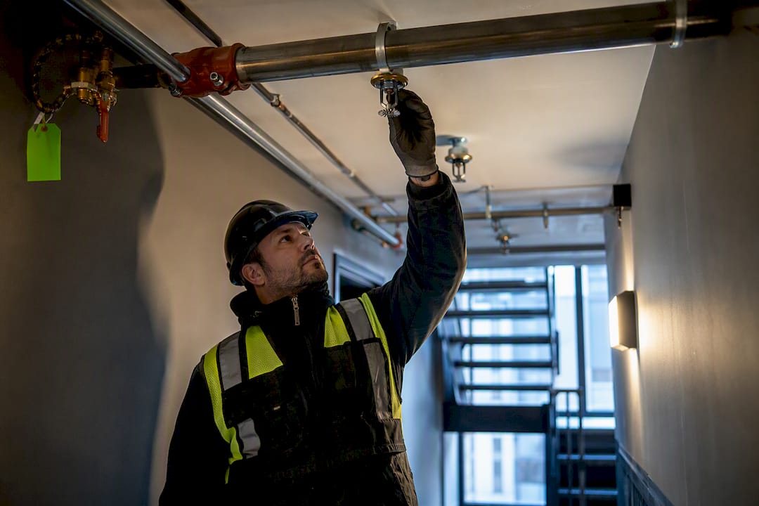 Technician inspecting NYC sprinkler retrofit piping