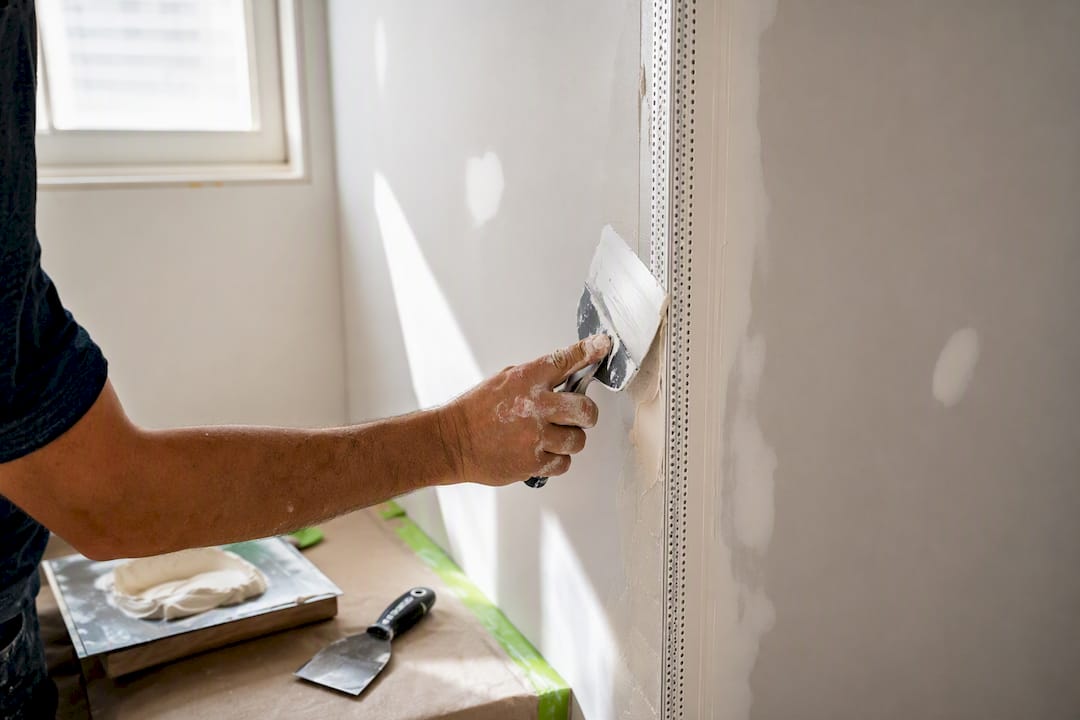 Worker embedding bead on drywall corner