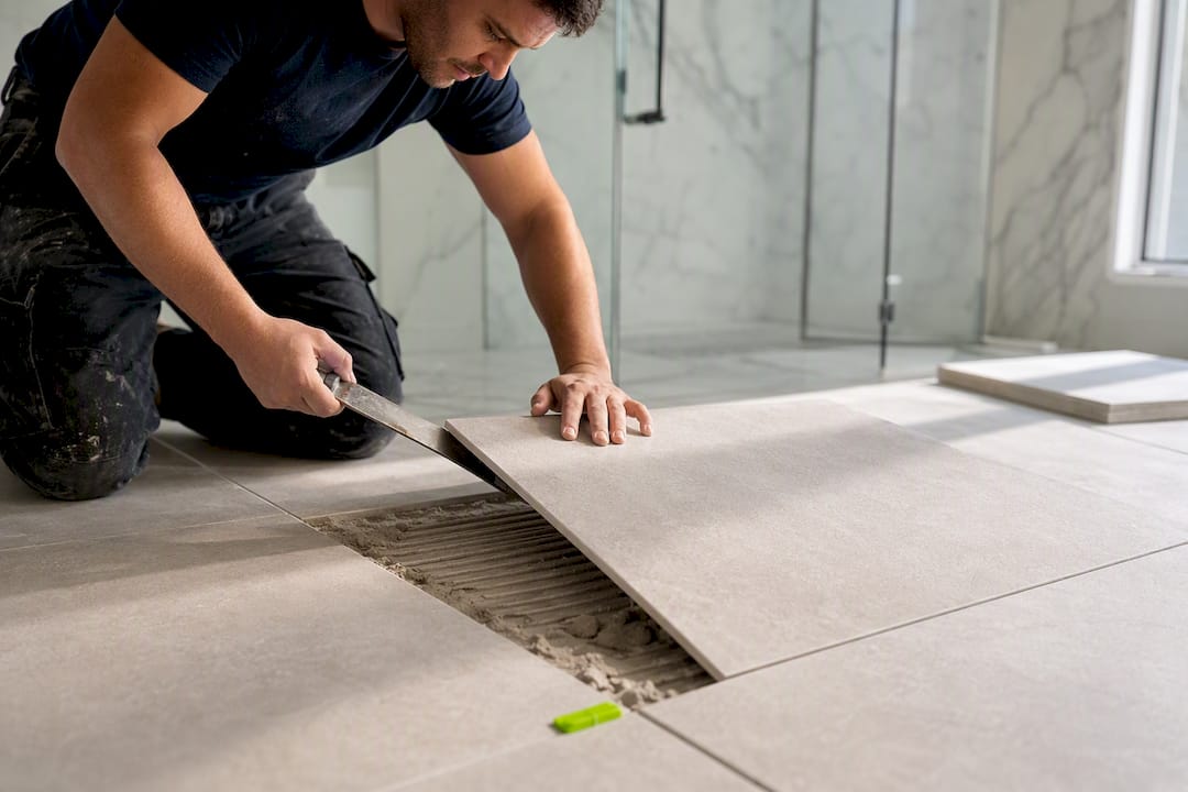 Installer correcting uneven tile placement