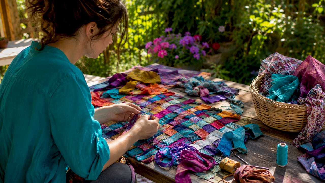 Hands sorting vintage fabrics and sewing tools