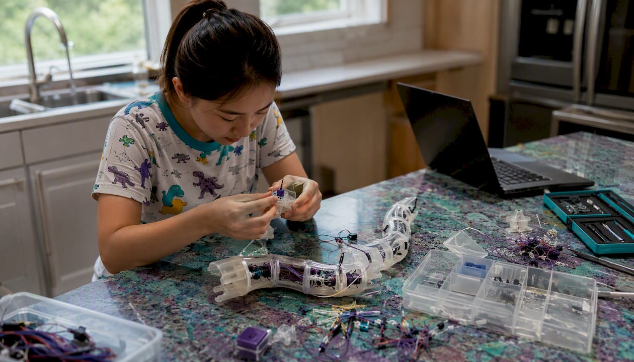 Woman assembling robotic snake segments at home