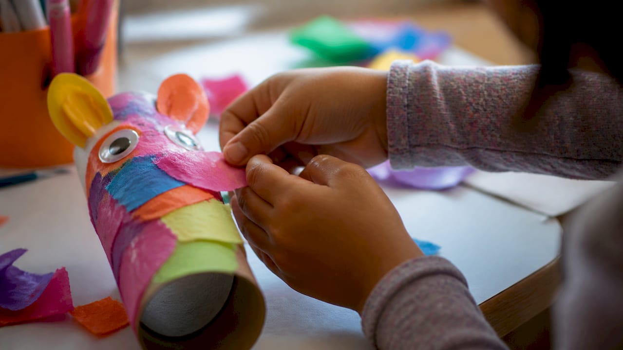 Child hands gluing animal puppet craft