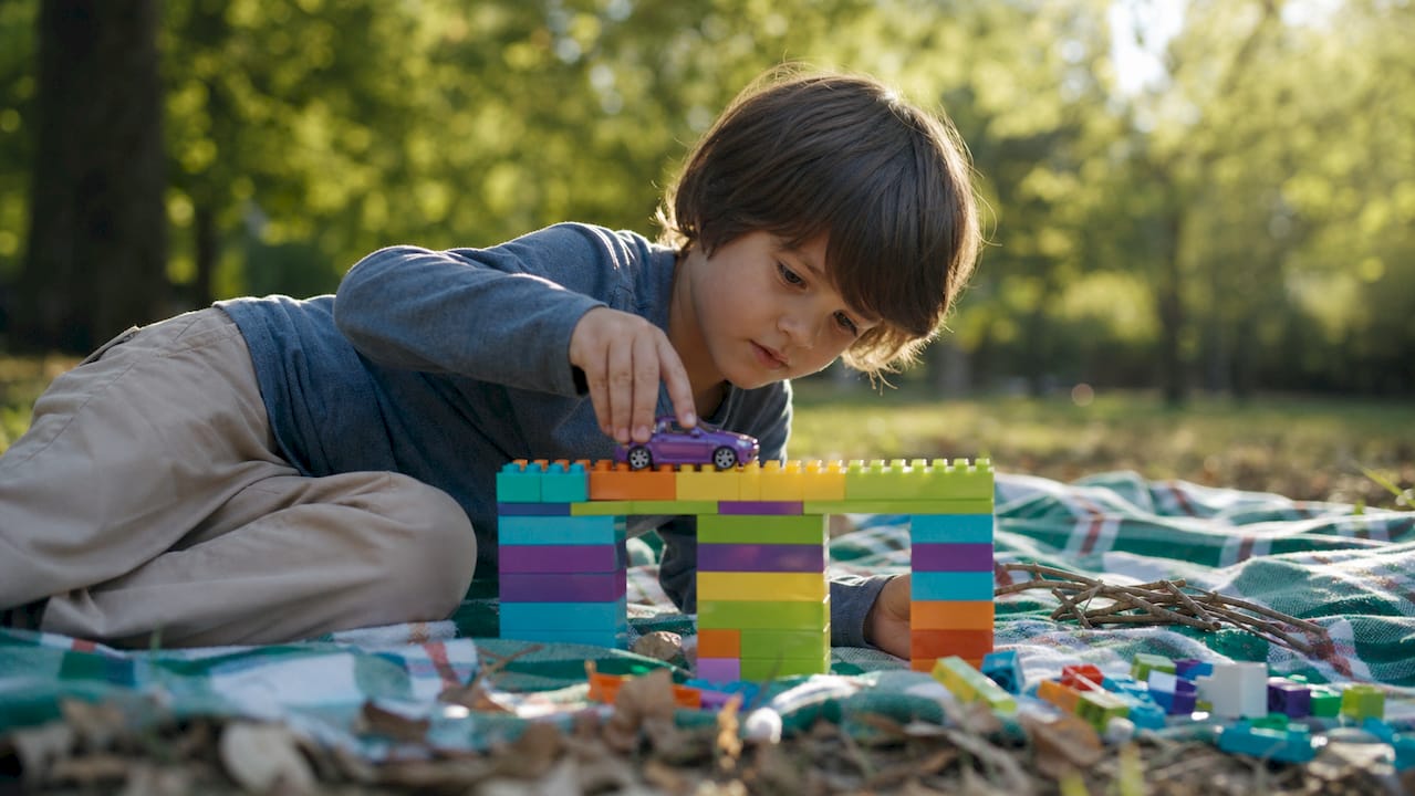 Child hands building bridge with blocks and toy car