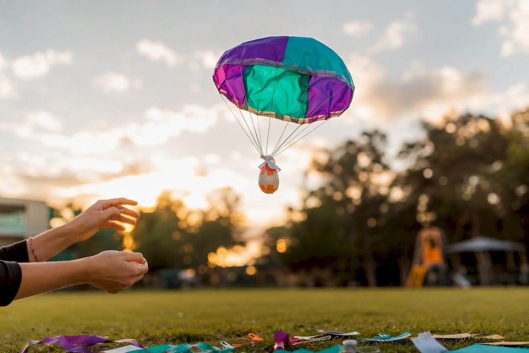 Hand releasing egg drop parachute indoors