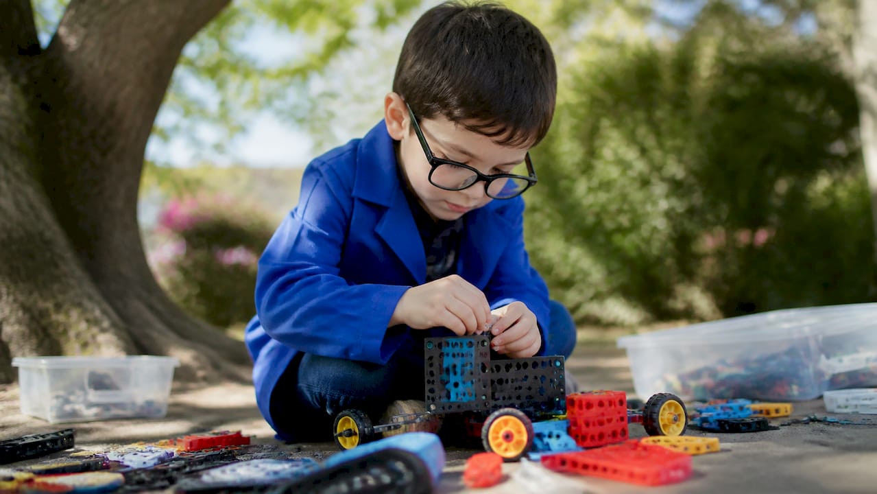 Child assembling STEAM kit wearing lab coat
