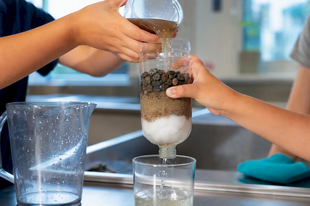 Hands testing a layered homemade water filter