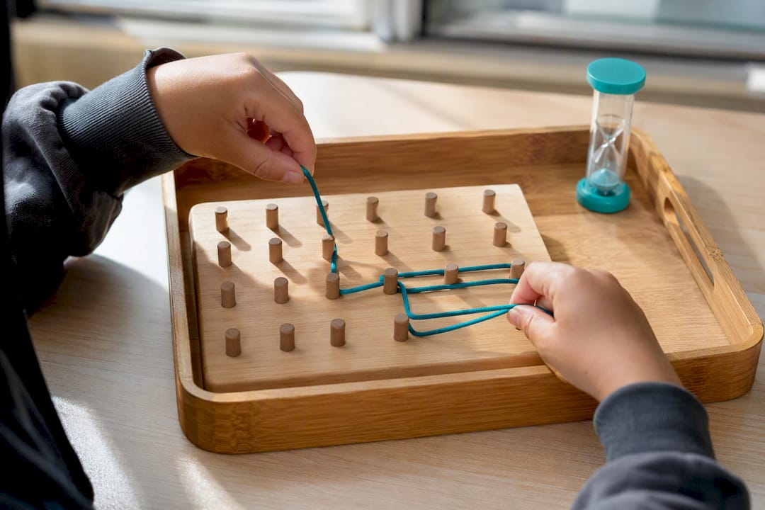 Child guiding lace through a pegboard