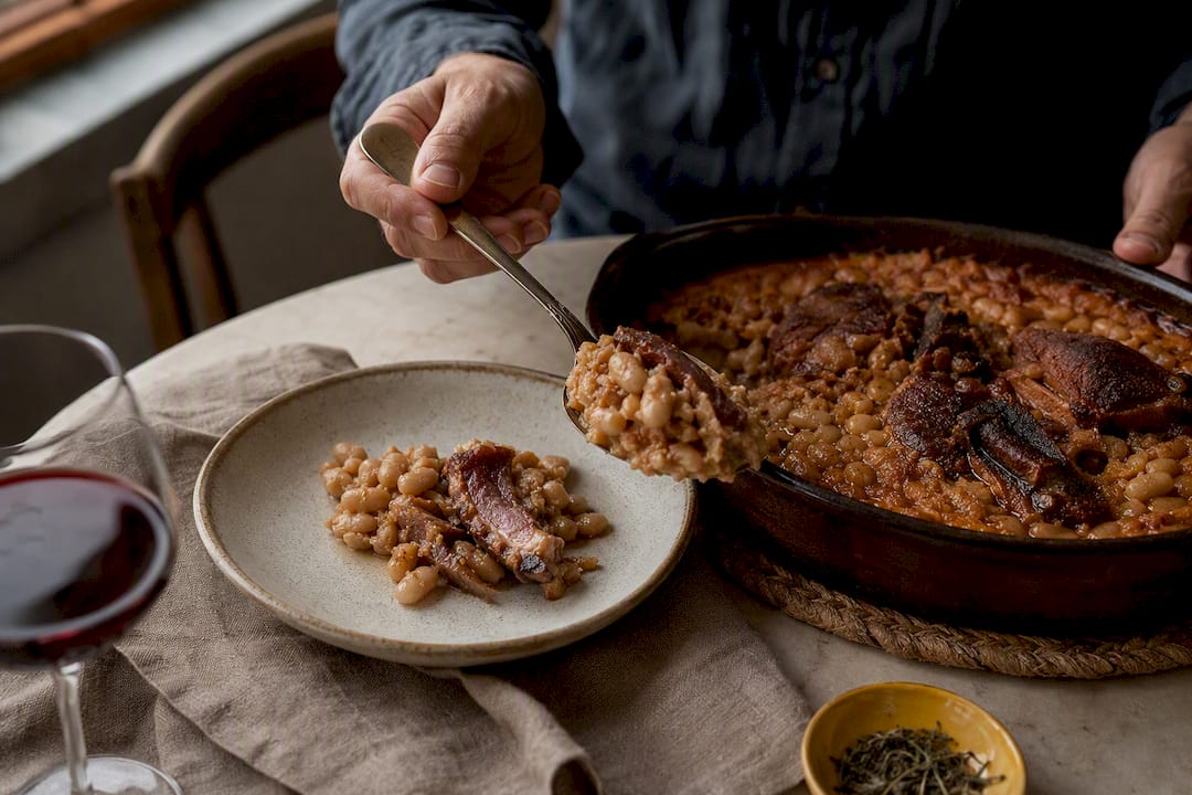 Cassoulet served beside an anonymous red wine glass