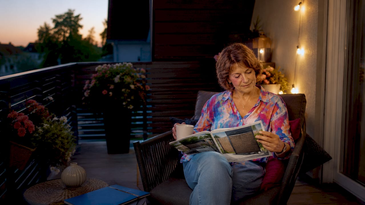 Die besten Zaundirekt.de Alternativen für Ihren Balkon 2026 4 Eine Frau sitzt am Tisch und entscheidet sich für einen Sichtschutz für ihren Balkon.