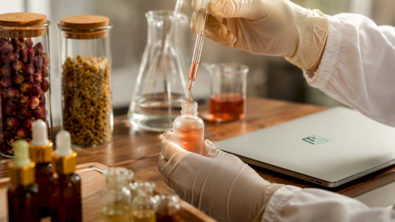 Hands preparing synthetic skincare serum in lab