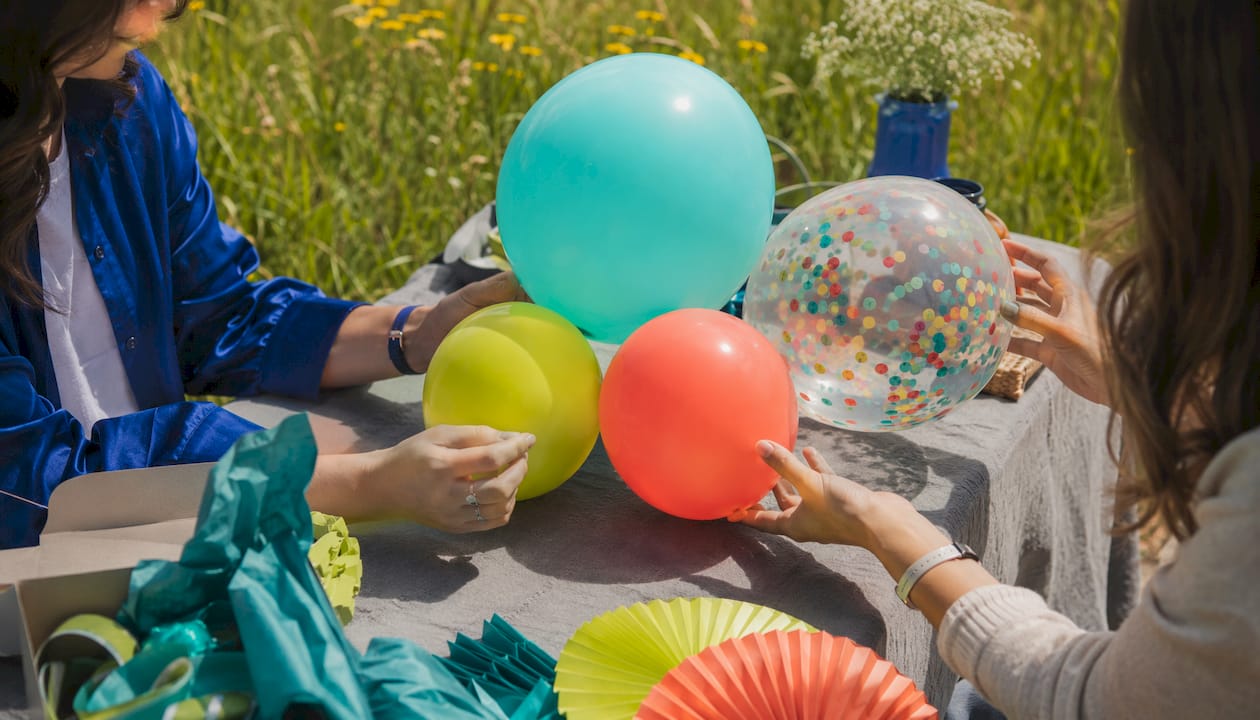 Hands comparing wedding balloon samples on desk