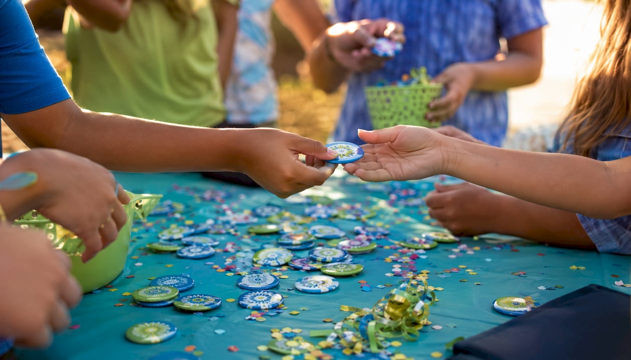Hands exchanging colorful birthday buttons on table