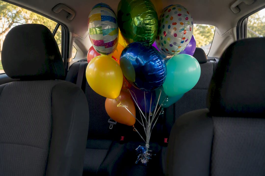 Helium balloon cluster secured in car back seat