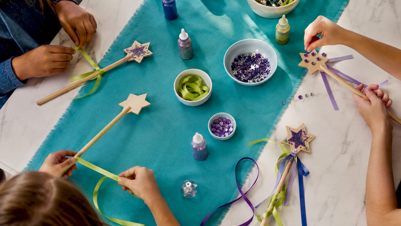 Hands decorating wands at party craft station