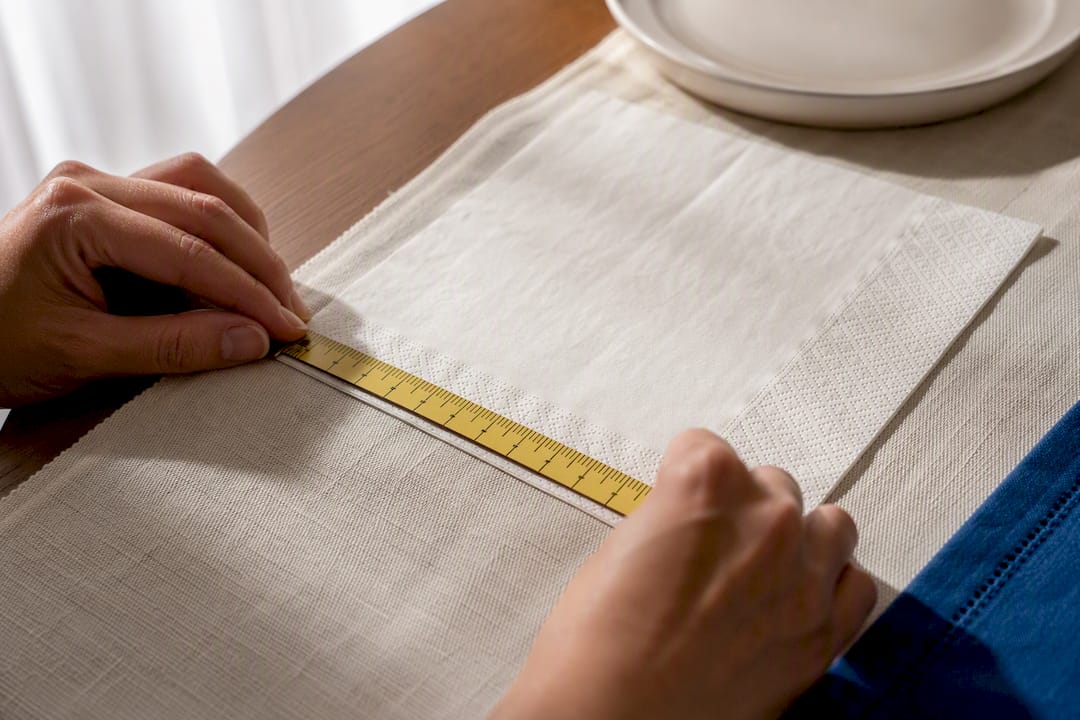 Hands measuring an unfolded napkin edge