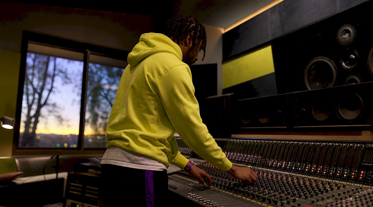 Hands adjusting audio mixer controls in studio