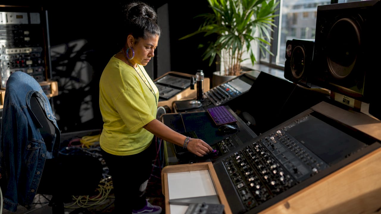 Hands adjusting subtractive EQ on mixing console