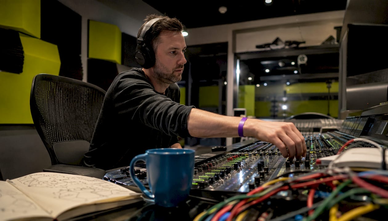Audio engineer adjusting mixing console in studio