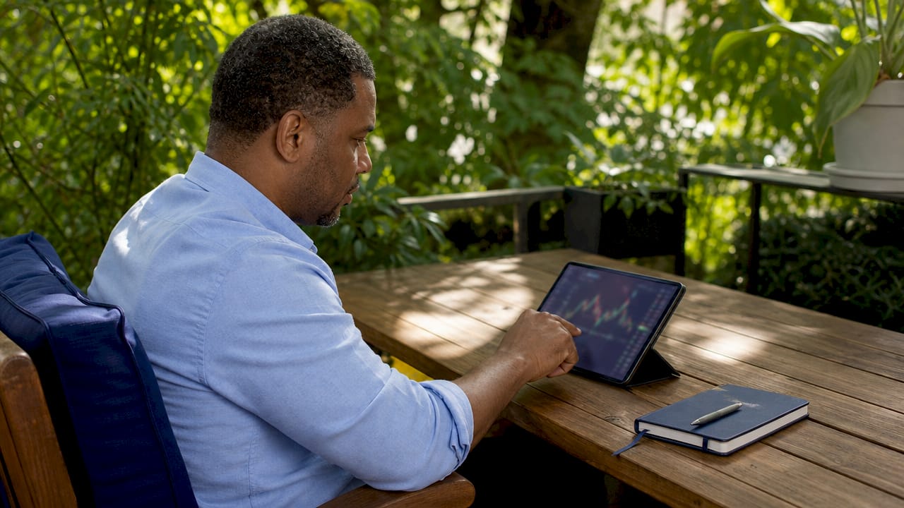 Hands scrolling financial data on tablet in coworking space