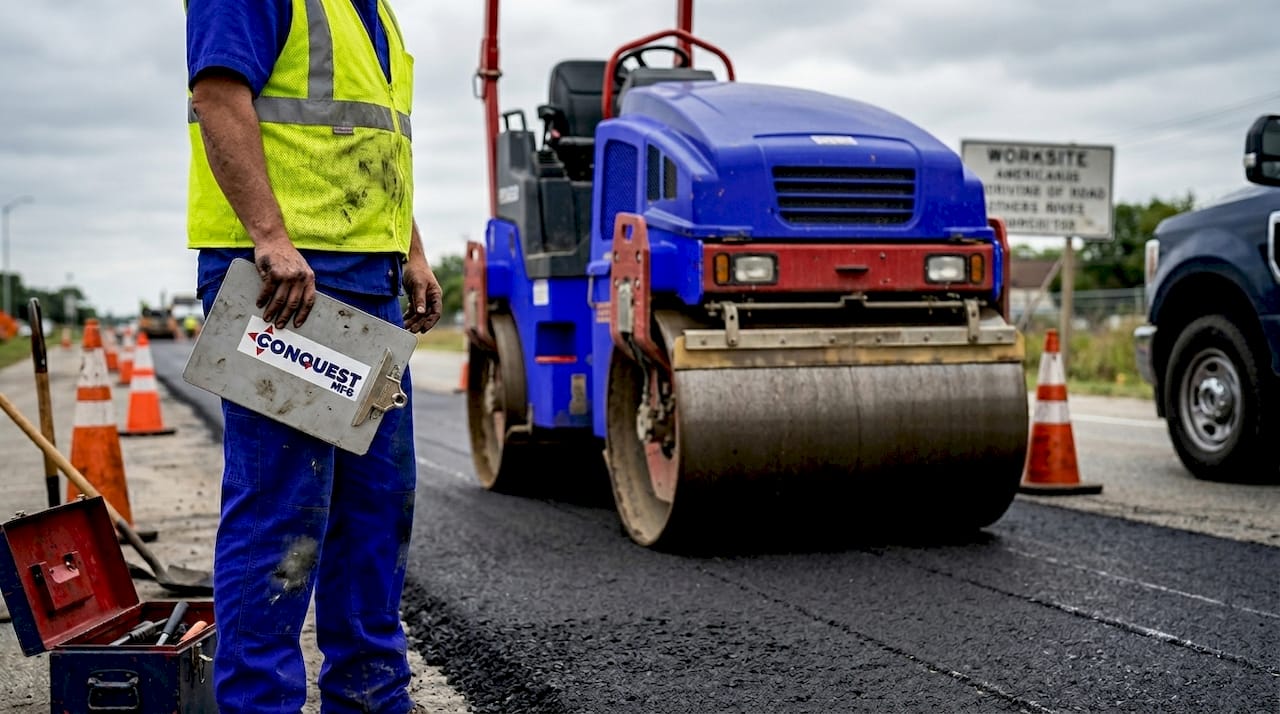 Foreman beside roller compactor on highway