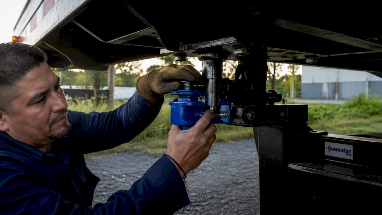 Hands installing king pin lock on trailer coupling